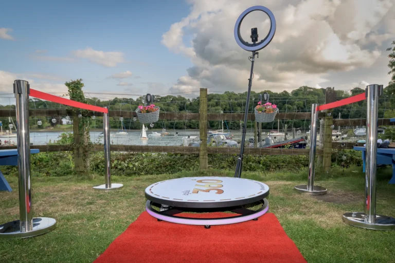 360 Photobooth with red carpet and rope barriers at School Promenade event. The students are dancing in the background having a good time.