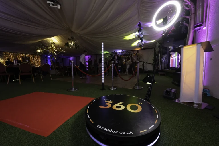 360 Photobooth with red carpet and rope barriers at School Promenade event. The students are dancing in the background having a good time.
