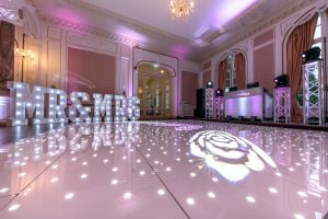 Beautiful wedding venue with starlit dance floor, white and pink venue uplighting and DJ setup.