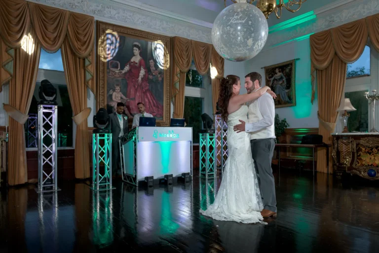 Bride and groom having romantic dance at wedding reception. Wedding DJ plays the first dance song. Green and white uplighting accentuate the room.