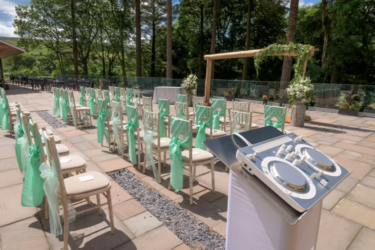 Outdoor wedding aisle in wooded area. Elegant disco system ready to play ceremony music.